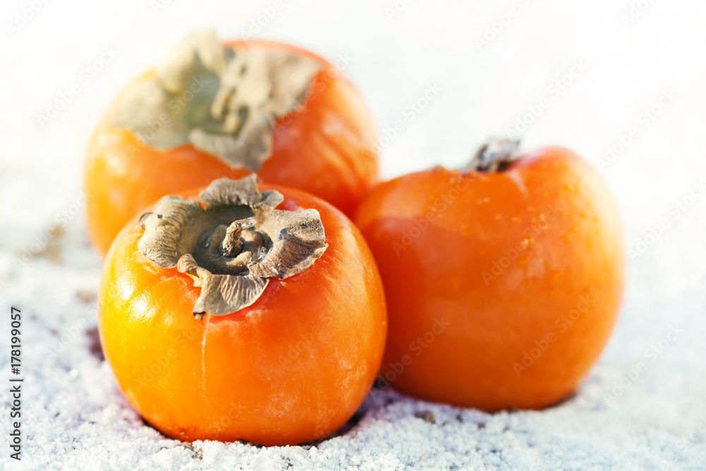 Delicious persimmons on white snow Delicious persimmons on white snow