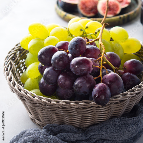 White and dark grapes in a basket on gray. Abstract minimal fruit still life