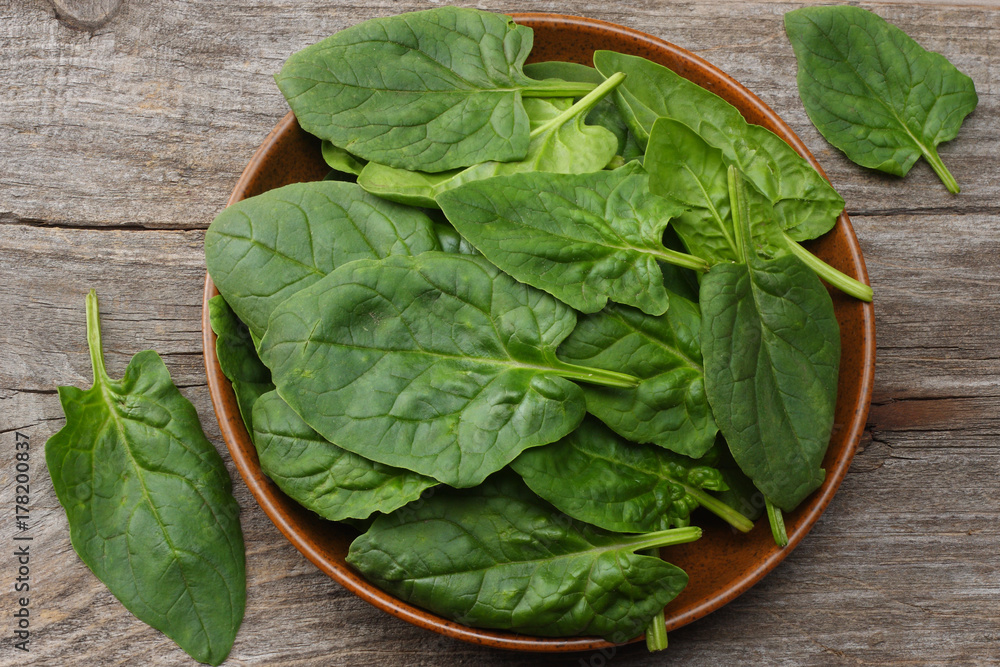 spinach leaves in bowl on old wooden table top view spinach leaves in bowl on old wooden table top view