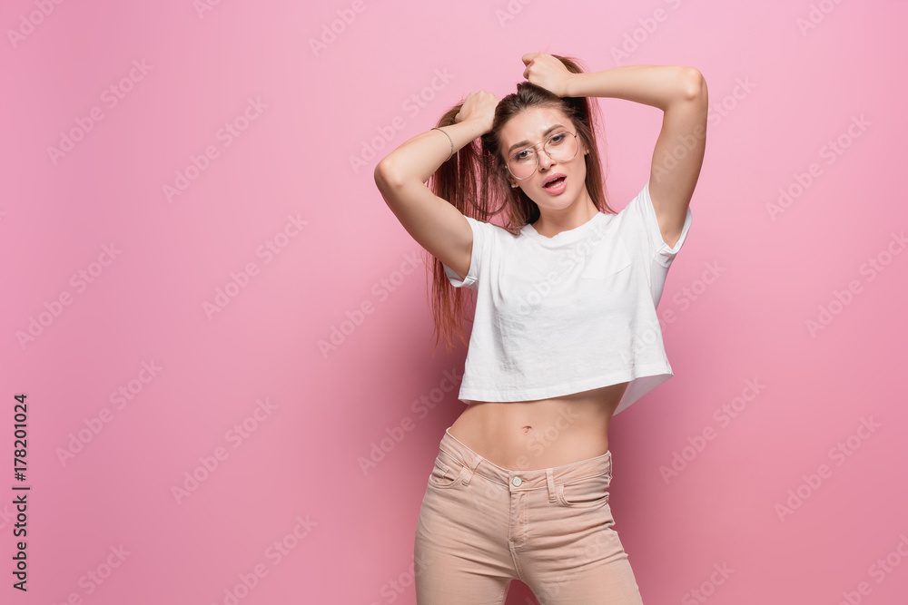 Pretty young sexy fashion sensual woman posing on pink background dressed in hipster style jeans Pretty young sexy fashion sensual woman posing on pink background dressed in hipster style jeans