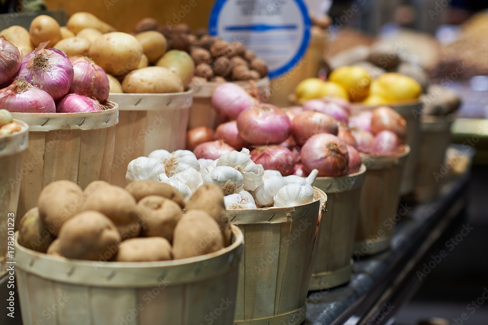 Garlic, potatoes and onions in wooden buckets on a market