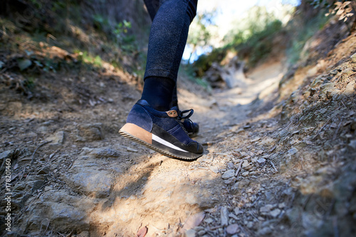 Woman walking on a forest trail with blue sport shoes