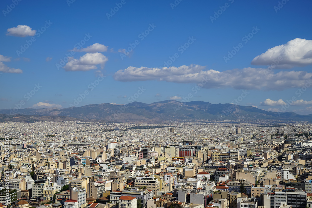 View of beautiful Athens city from Acropolis showing white buildings architecture, mountain, trees, blue sky and floating white cloud background