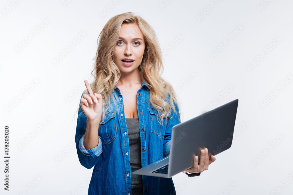 Pleasant woman making remark while holding laptop Pleasant woman making remark while holding laptop