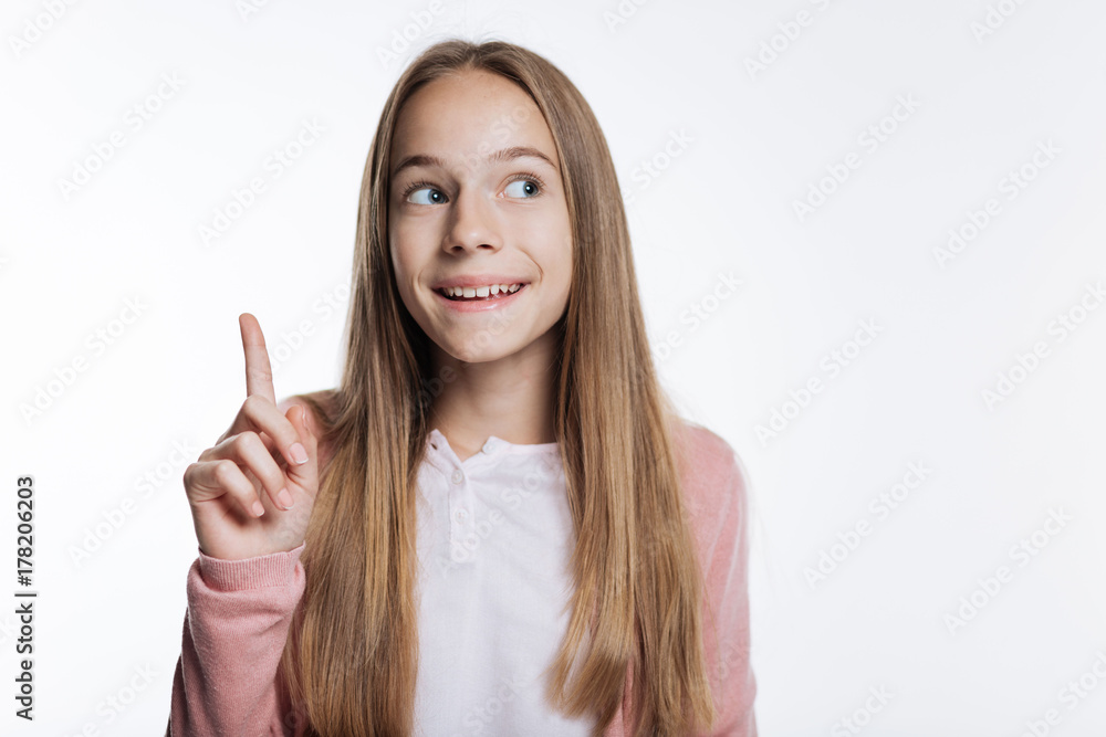 Smiling teenage girl pointing up with her finger Smiling teenage girl pointing up with her finger