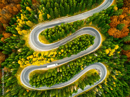 Lorry winding up its way on a curvy road through autumn colored 