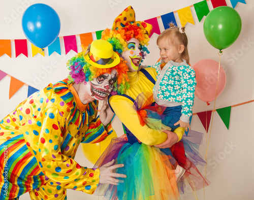 a terrible clown and a good clown with a child. Halloween. The crazy clown and clowness. Little girl