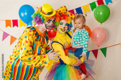 a terrible clown and a good clown with a child. Halloween. The crazy clown and clowness. Little girl