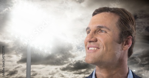 Man looking up with stadium lights and clouds background