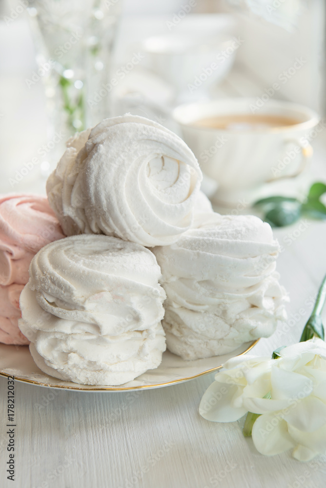 Soft vanilla meringue dessert with white flowers, wooden background