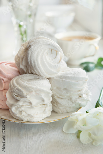 Soft vanilla meringue dessert with white flowers  wooden background