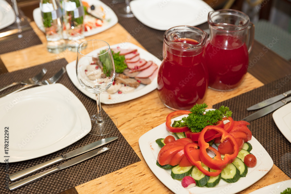 festive served table in restaurant. vegetable plate, meat plate and fruit drink in jug