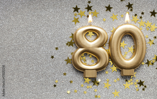 Number 80 gold celebration candle on star and glitter background