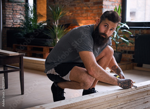 Carpenter measuring boards in a room with loft interior.