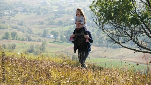 Happy father and little daghter walking in autumn meadow and having fun. photo