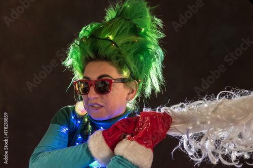 Splended girl with green hair dressed in Christmas garlands. A girl is depicting a Christmas tree. The concept of a good mood on a holiday. photo