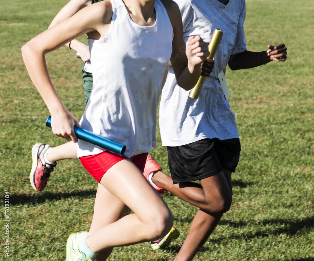 High School Girls racing a relay on a grass field High School Girls racing a relay on a grass field