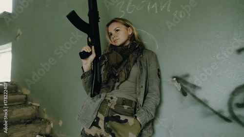 Young attractive military woman holding automatic rifle and looking at camera. photo