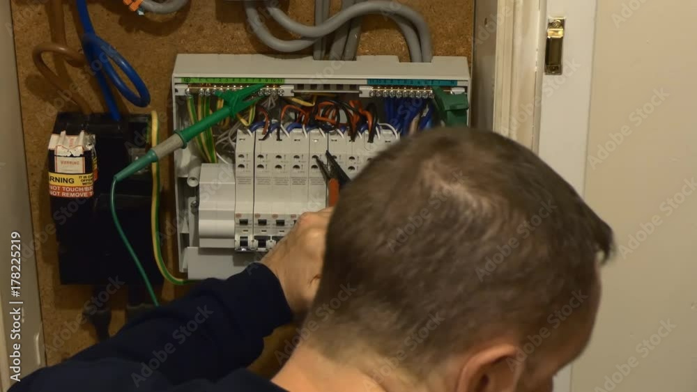 Electrician opened fuse box and testing house electrical circuits for