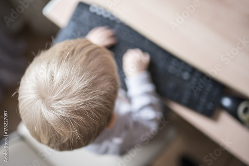 A small child prints on the keyboard