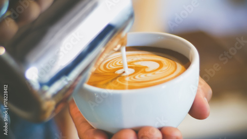 Fotografia barista pouring streamed milk to make heart shape latte art in cup of hot coffee