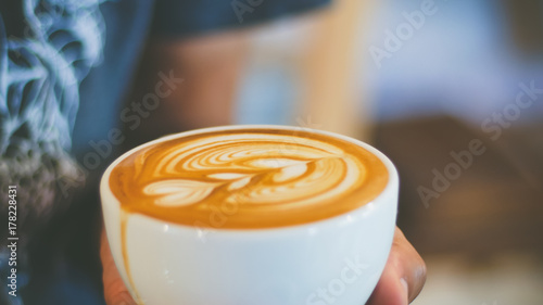 barista pouring streamed milk to make heart shape latte art in cup of hot coffee, retro tone