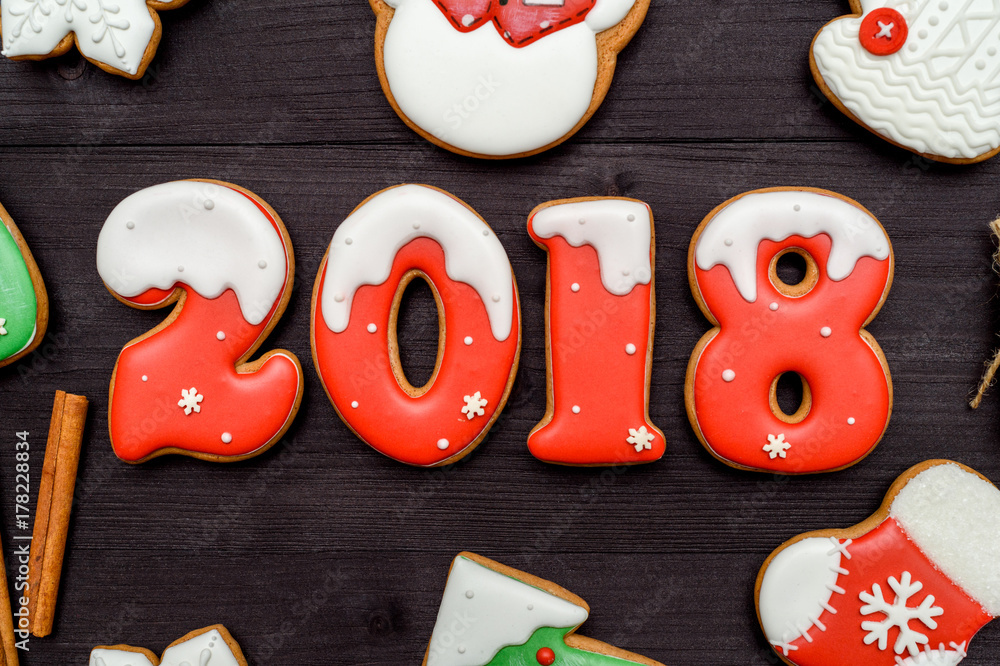 Happy new year 2018 sign symbol with red and white gingerbread cookies on dark wooden background, copy space. Top view, flat lay. Christmas cookies, free space