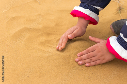 Yellow sand with kids hands on it photo