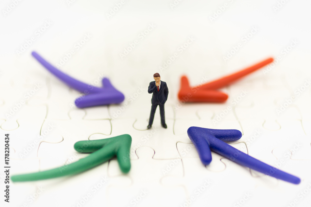 Miniature people: Businessman standing in front of arrow pathway choice using as Business decision concept. Miniature people: Businessman standing in front of arrow pathway choice using as Business decision concept.