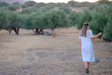 Young beautiful girl in a dress near the olive tree. View from the back