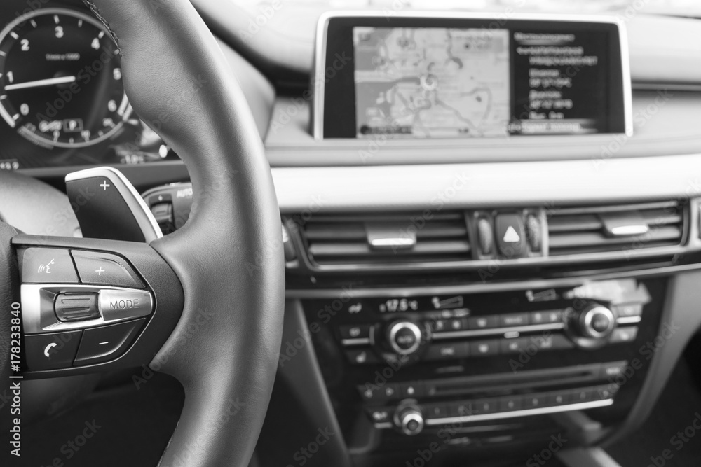Modern car interior, red steering wheel with media phone control buttons,navigation, screen multimedia system background, car interior details. Black and white