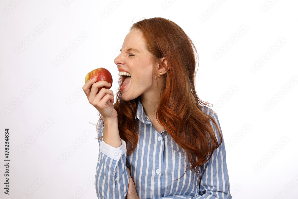 Hübsche rothaarige Frau beisst in einen Apfel