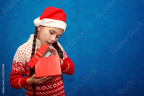 Happy little smiling girl with Christmas gift box on blue background color © olgasparrow