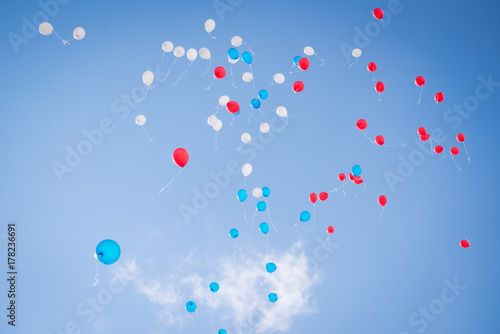 Balloons of red blue and white colors flying in the blue sky with clouds