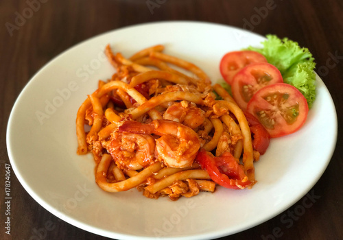 Stir fried macaroni or pasta with tomato sauce and topped with shrimp, selective focus