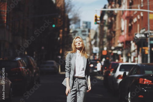 Woman in grey suit poses on the street of New York in a windy day
