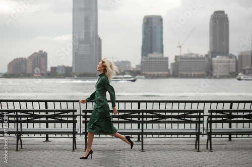 Tablou pe pânză Thoughtful woman runs in her elegant dress along the river shore in New York