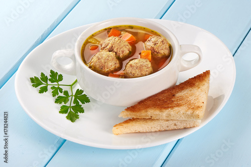 A bowl of soup with meatballs with toasted bread