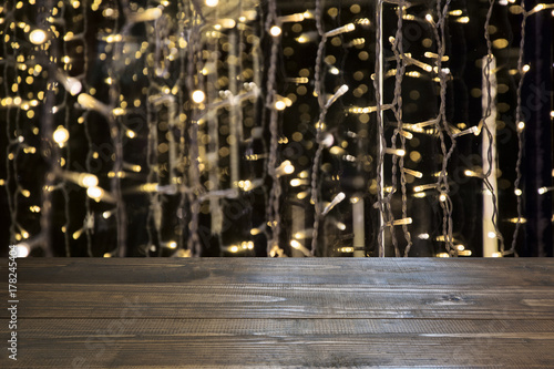 Blurred gold garland and wooden tabletop as foreground. Image for display or montage your christmas products.