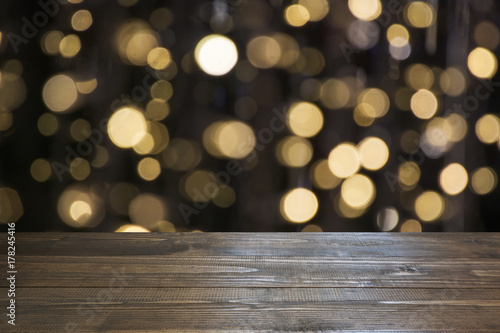 Blurred gold garland and wooden tabletop as foreground. Image for display or montage your christmas products.