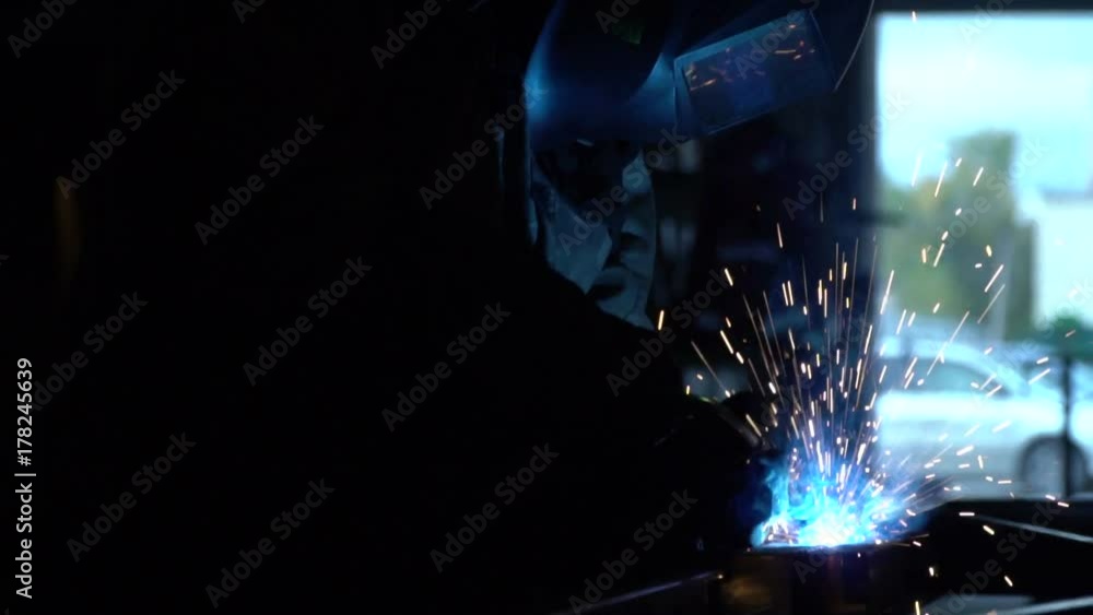 Blue light and smoke from welding. Sparks against a dark background from welding. The man the welder in a languid barn. Welder at work in metal industry. Slow motion Blue light and smoke from welding. Sparks against a dark background from welding. The man the welder in a languid barn. Welder at work in metal industry. Slow motion
