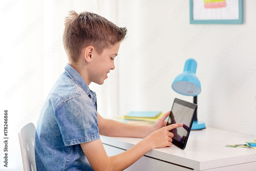 smiling boy with tablet pc sitting at home desk