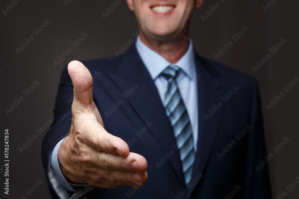 A smiling man holds out his hand for a handshake A smiling man holds out his hand for a handshake