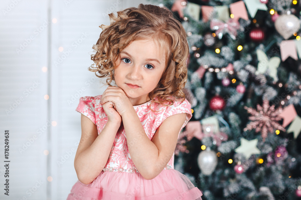 portrait of a little blonde girl with curls near a tree with brightly colored lanterns and flags portrait of a little blonde girl with curls near a tree with brightly colored lanterns and flags