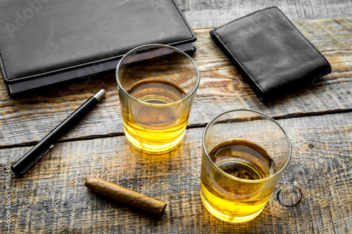 Drink whiskey in the evening. Glasses, wallet, cigar on rustic wooden background