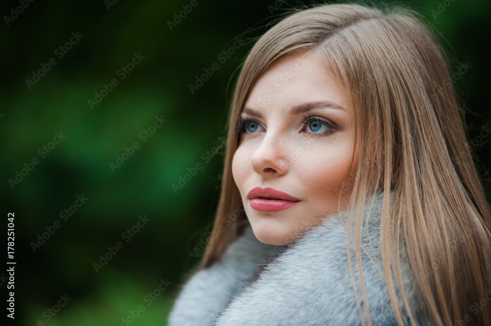 Fototapeta premium Beautiful young blonde woman wearing fur autumn coat