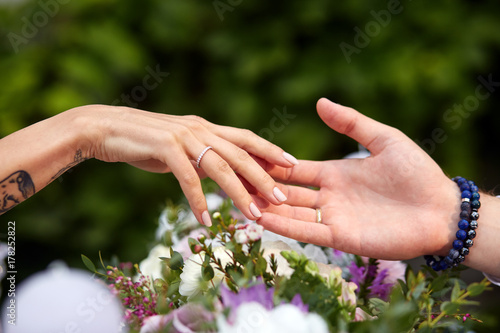 Man's and woman's hands touch each other tender over a bouquet