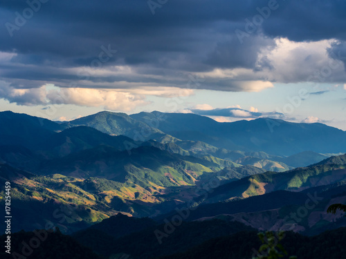 The nature moment where the sun is clear out the shade from cloudy sky by its sunlight toward the valley of mountain. This landscape moment can be seen while trekking to on Doi Phu Wae, Nan, Thailand © yosanon