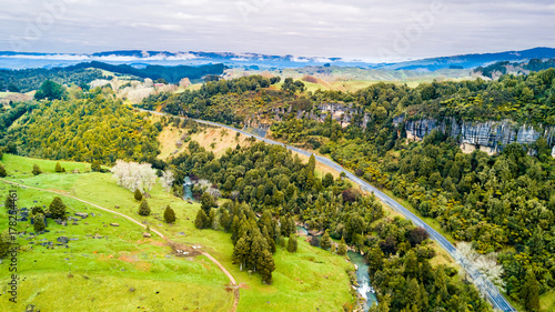 Aerial view on a road running along a river through mountain valley with rocks on the background. Taranaki region, New Zealand © Dmitri