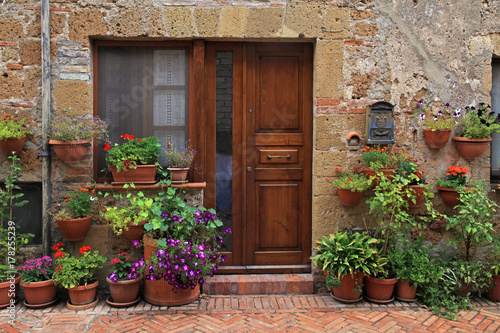 old wooden door decorated with flower pots from the medieval town, Tuscany, Italy © Inna Felker